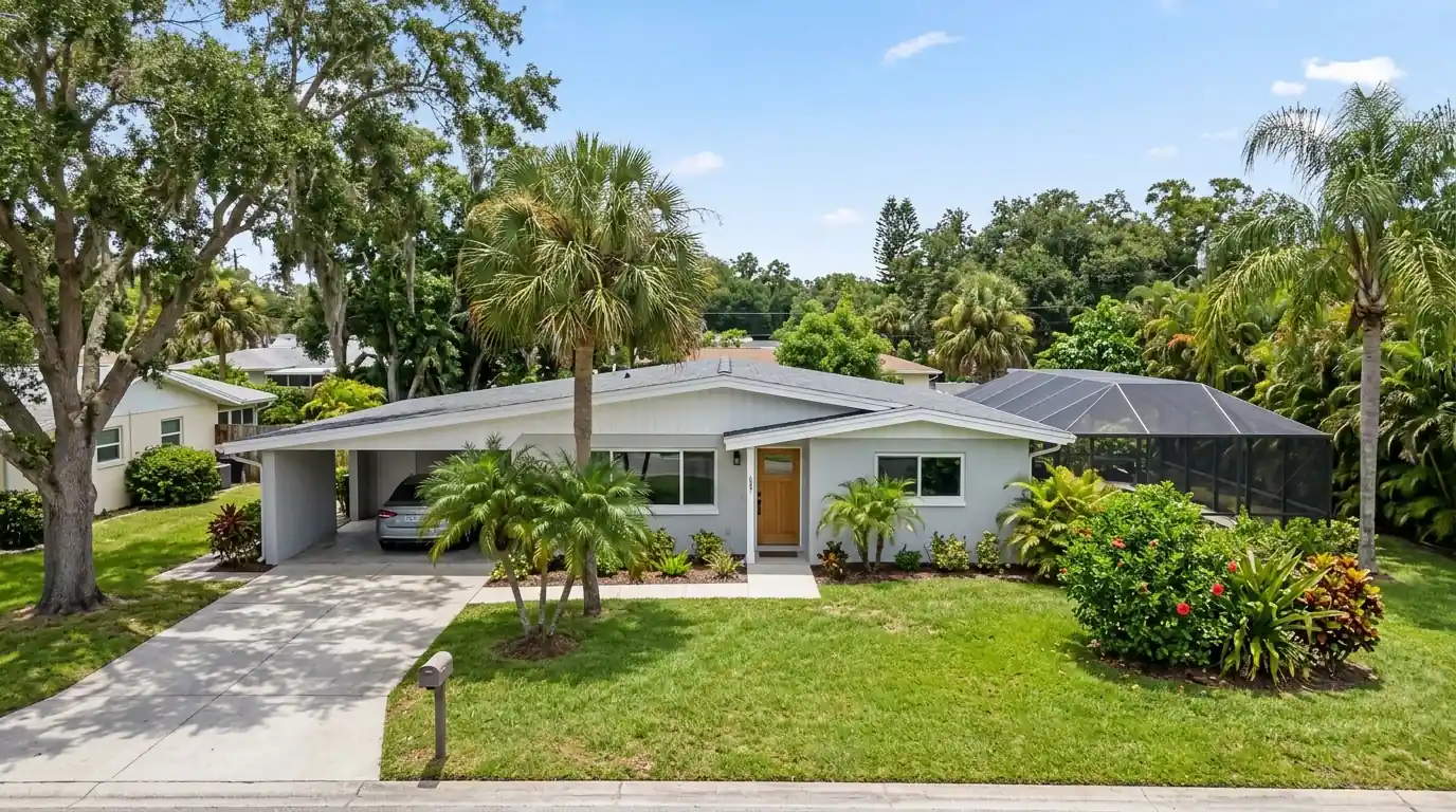 Mid-century ranch home in Arlington Park, Sarasota, with fresh light gray stucco, white fascia and a screened pool cage in back