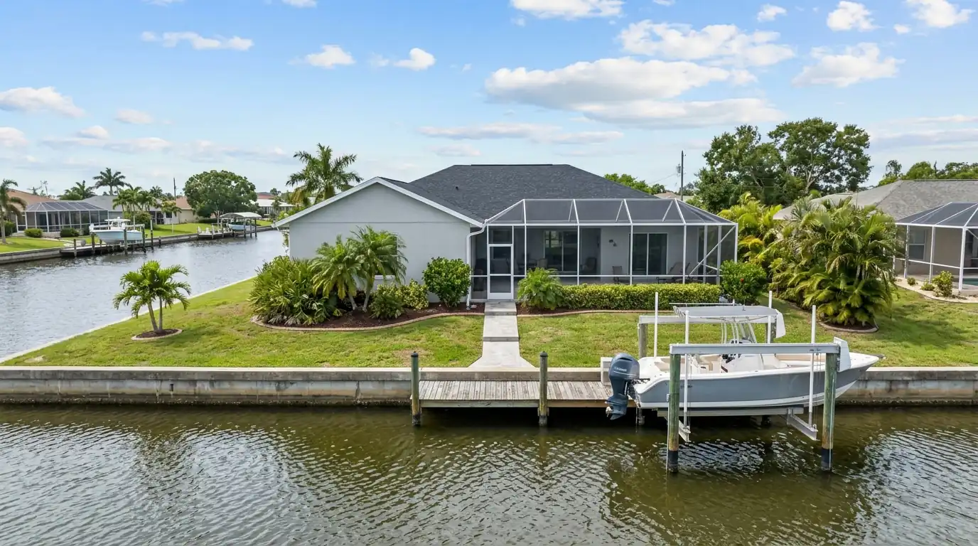 Light gray block ranch home with a screened lanai backing onto a canal with a boat lift in Port Charlotte