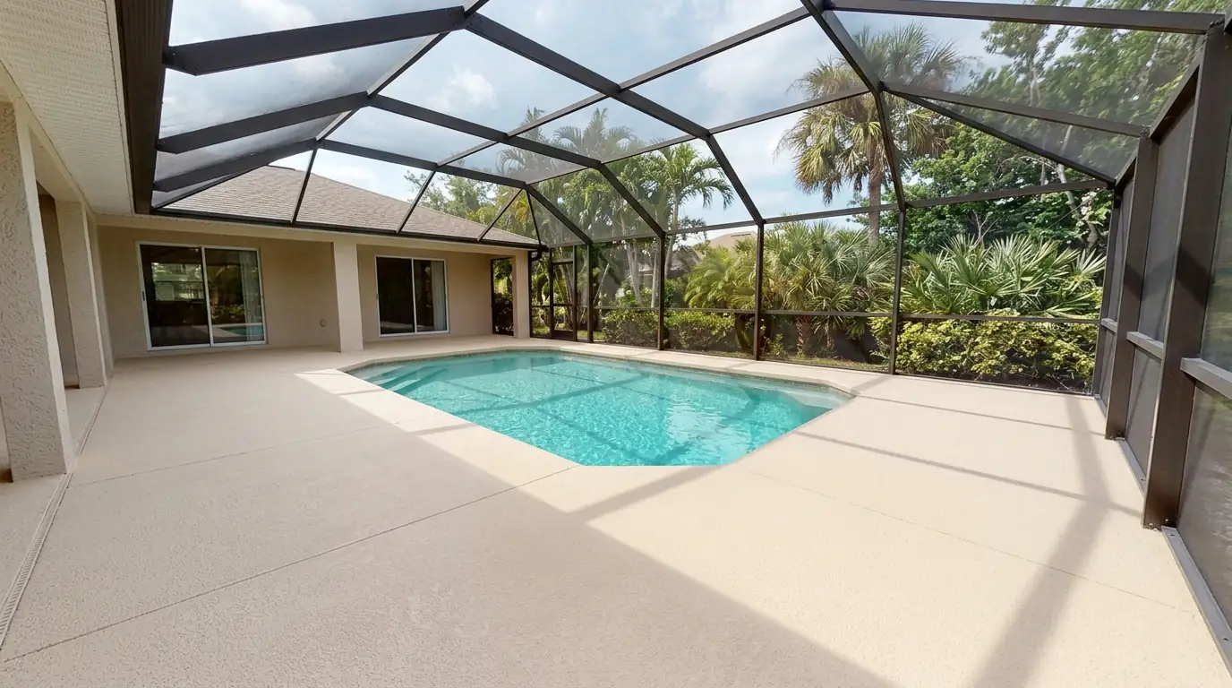 Freshly coated light sand textured pool deck around a turquoise pool under a screened lanai in Sarasota